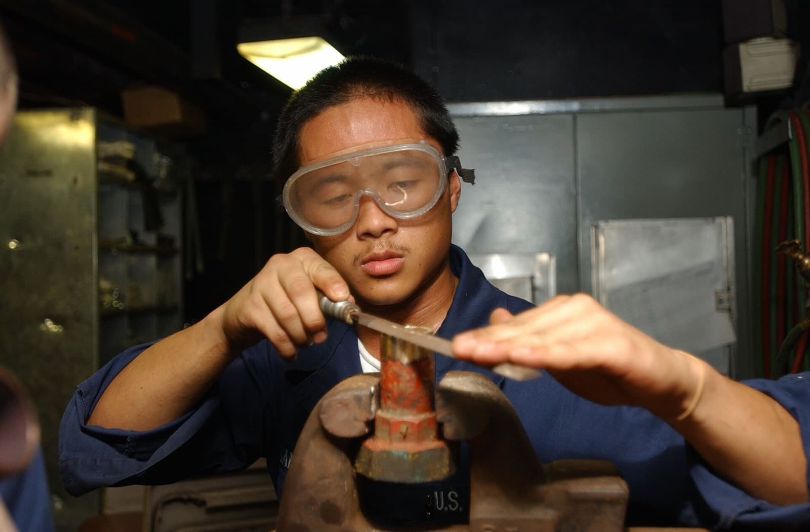 Tradesperson repairing a pipe fitting at a bench