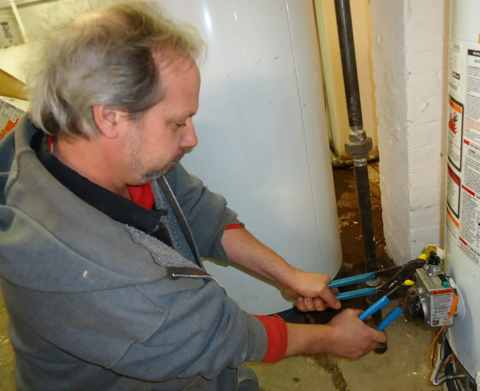 Plumber tightening a fitting on a water heater